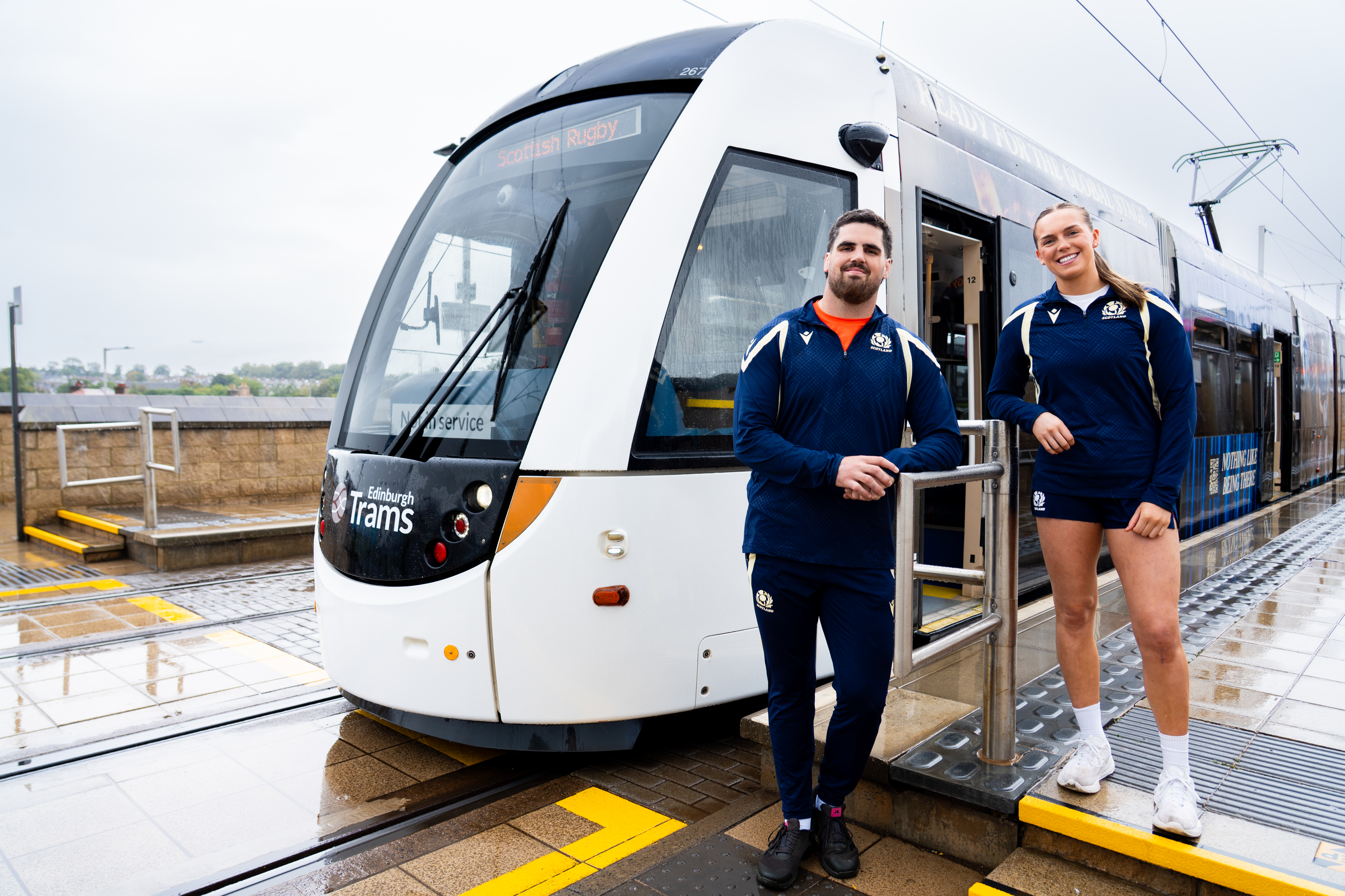 Two Scottish Rugby players standing next to a tram at Murrayfield Stadium