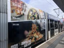 an image of a tram with an advert for the St James Quarter Seafood Festival
