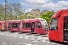 Two trams passing each other on Princes Street with Edinburgh Castle in the background