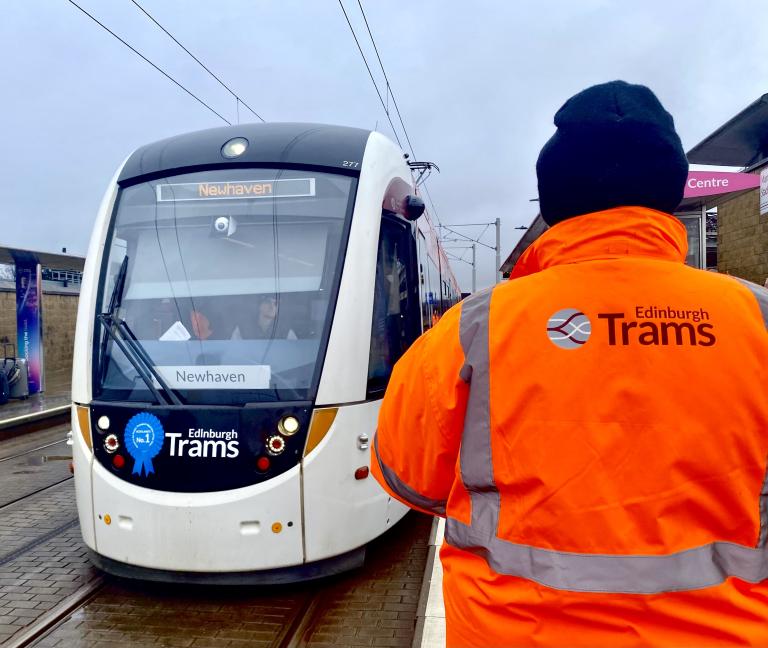 A colleague from Edinburgh Trams standing on the platform at Murrayfield watching a tram approaching.