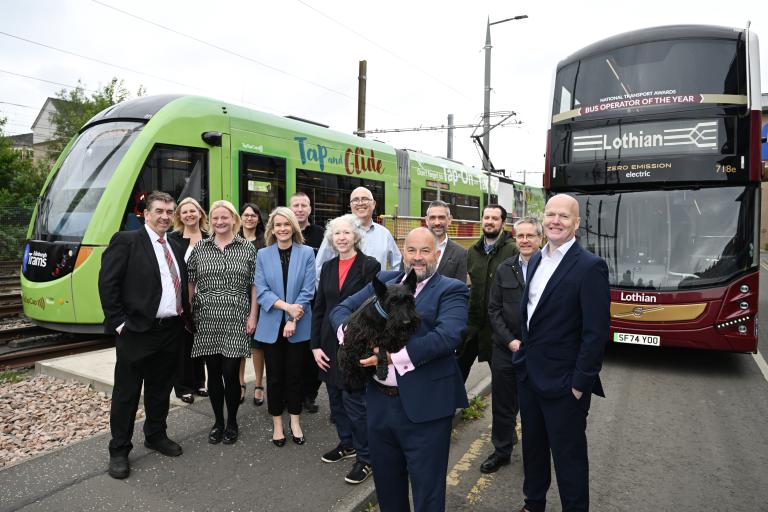 A group of staff with a tram and bus