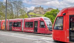 Two trams passing each other on Princes Street with Edinburgh Castle in the background