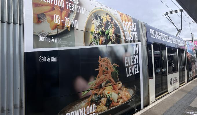 an image of a tram with an advert for the St James Quarter Seafood Festival