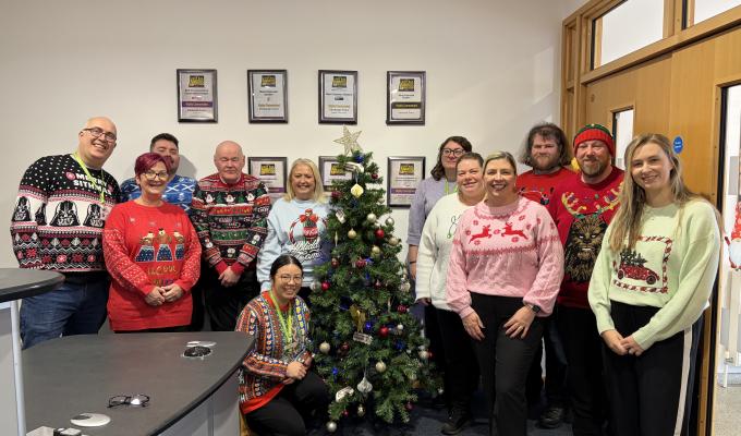 Edinburgh Trams colleagues in Christmas jumpers in front of a Christmas tree