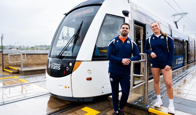 Two Scottish Rugby players standing next to a tram at Murrayfield Stadium